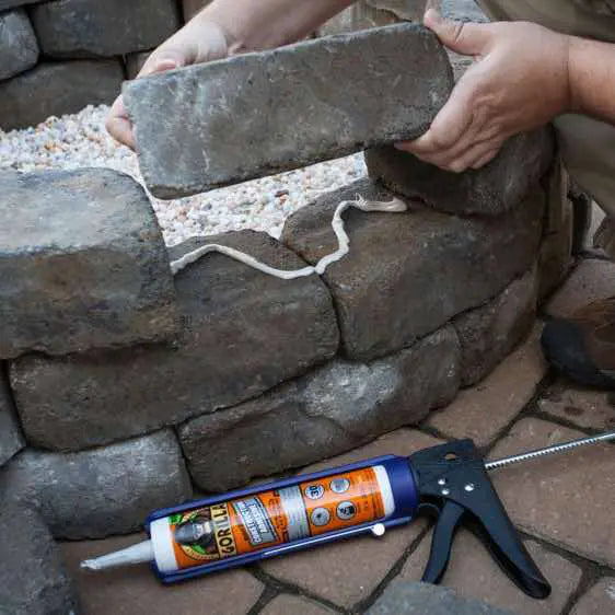 gorilla sealant being used to glue stones to a wall outdoor